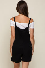 woman wearing a black maternity romper with spaghetti straps and a white off-shoulder top underneath