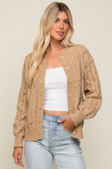 woman wearing a tan cable knit cardigan sweater over a white top and light wash denim jeans