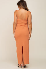 Back view of a woman wearing a long orange ribbed knit maxi dress with a back slit and square neckline