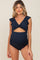 woman wearing a navy blue maternity swimsuit with ruffle sleeves and cutout detail highlighting her baby bump