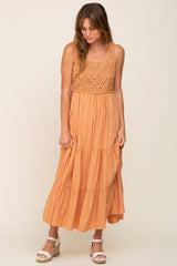 woman wearing an orange sleeveless maxi dress with a crochet bodice and tiered skirt