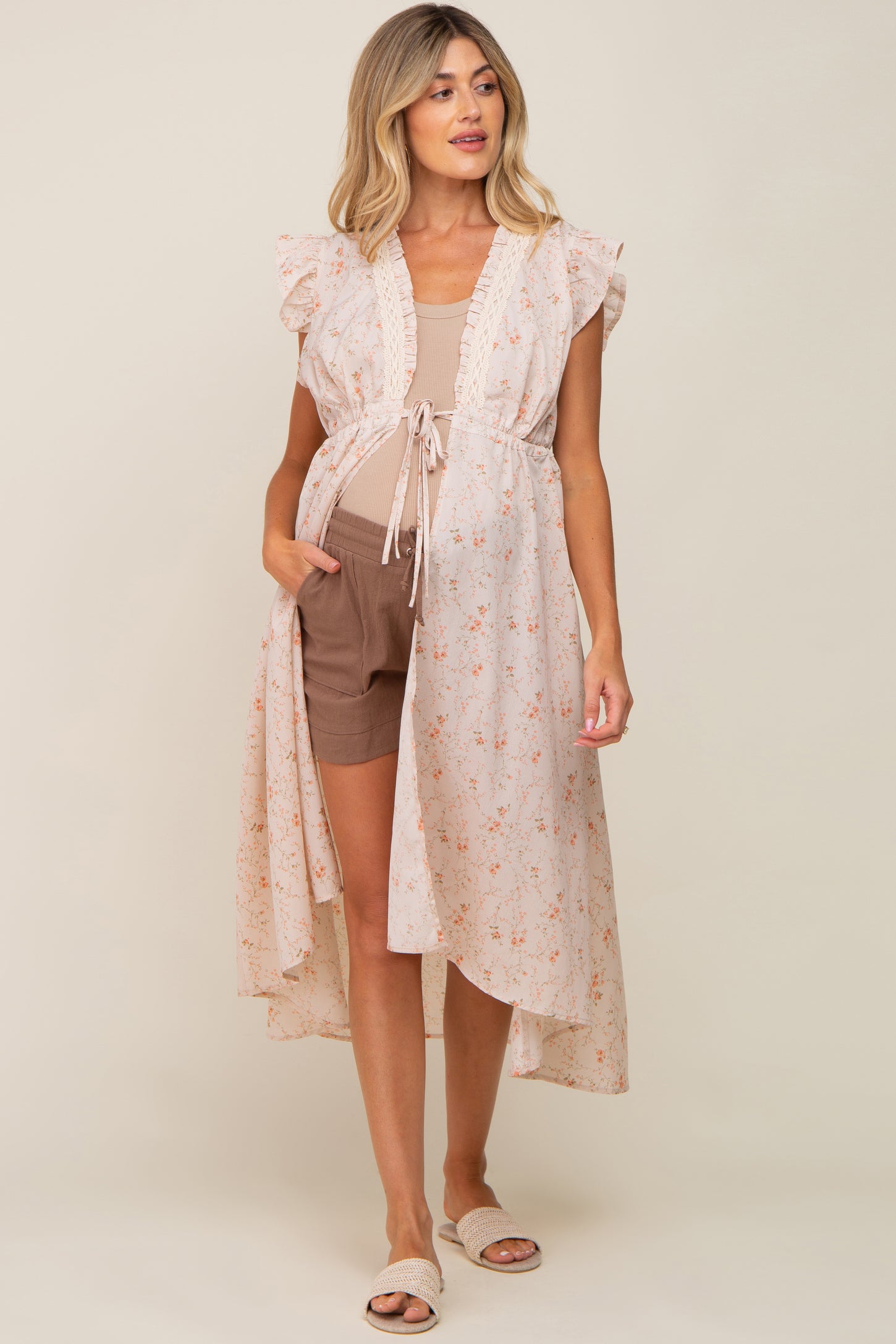 woman wearing floral maternity kimono over tan top and brown shorts