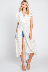 woman wearing a white floral print long kimono with ruffle sleeves over denim shorts and wedge sandals