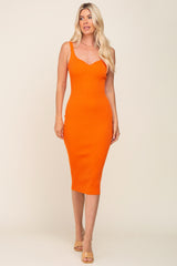 blonde woman wearing a sleeveless orange ribbed midi dress and tan heels against a neutral background