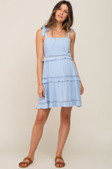 Woman wearing a light blue tie-shoulder maternity dress with tiered ruffles and crochet lace trim