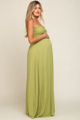 pregnant woman in a sage green smocked maternity maxi dress posing against a neutral background