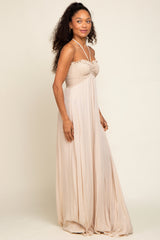 woman wearing a flowy beige maxi dress with a smocked bodice and halter neckline