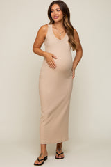 woman wearing a beige sleeveless maternity dress and holding her baby bump, styled with black sandals