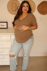 woman wearing a brown short sleeve maternity top and distressed light blue jeans, showing her baby bump