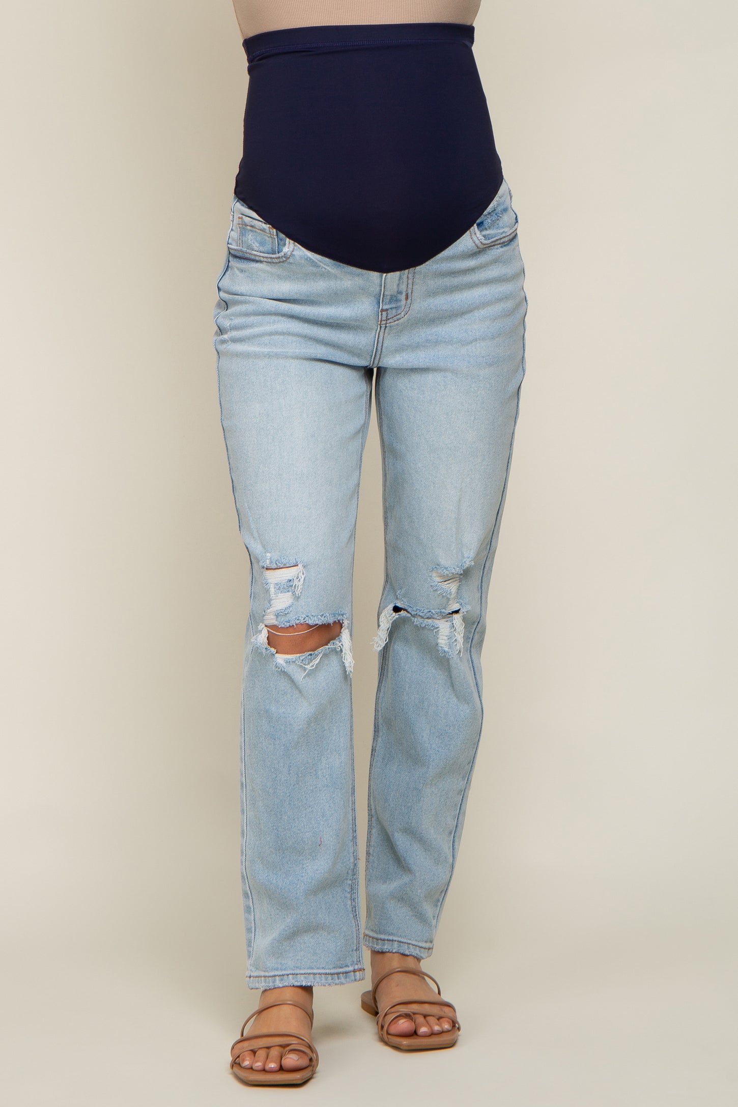 woman wearing light blue distressed maternity jeans with a high navy waistband