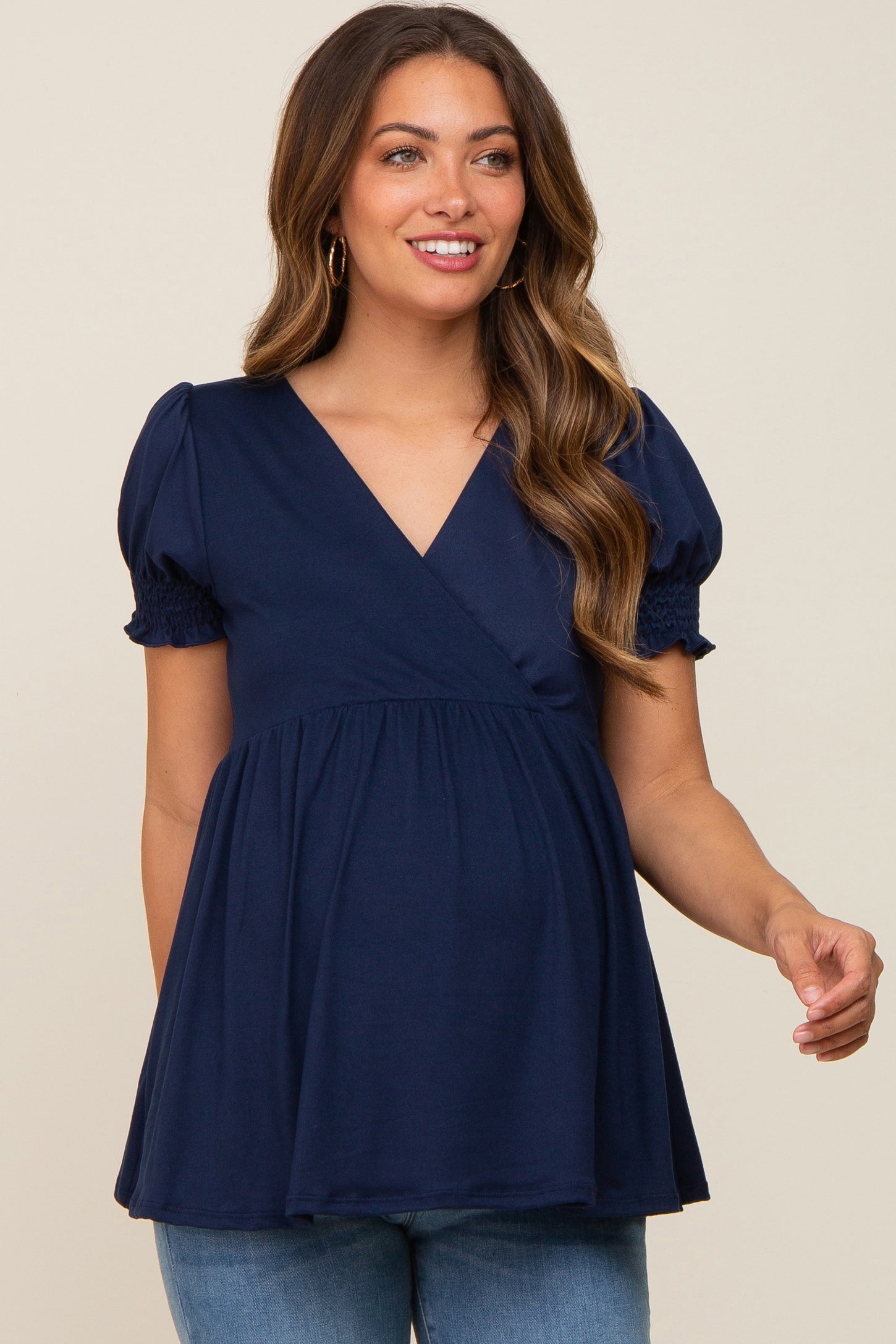 woman wearing a navy blue maternity top with short puff sleeves and a wrap design, featuring a baby bump