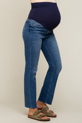 woman wearing dark blue maternity jeans with a stretchy waistband, showing her baby bump, paired with green sandals