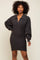 Woman wearing a charcoal grey ribbed knit sweater dress with a collar and balloon sleeves
