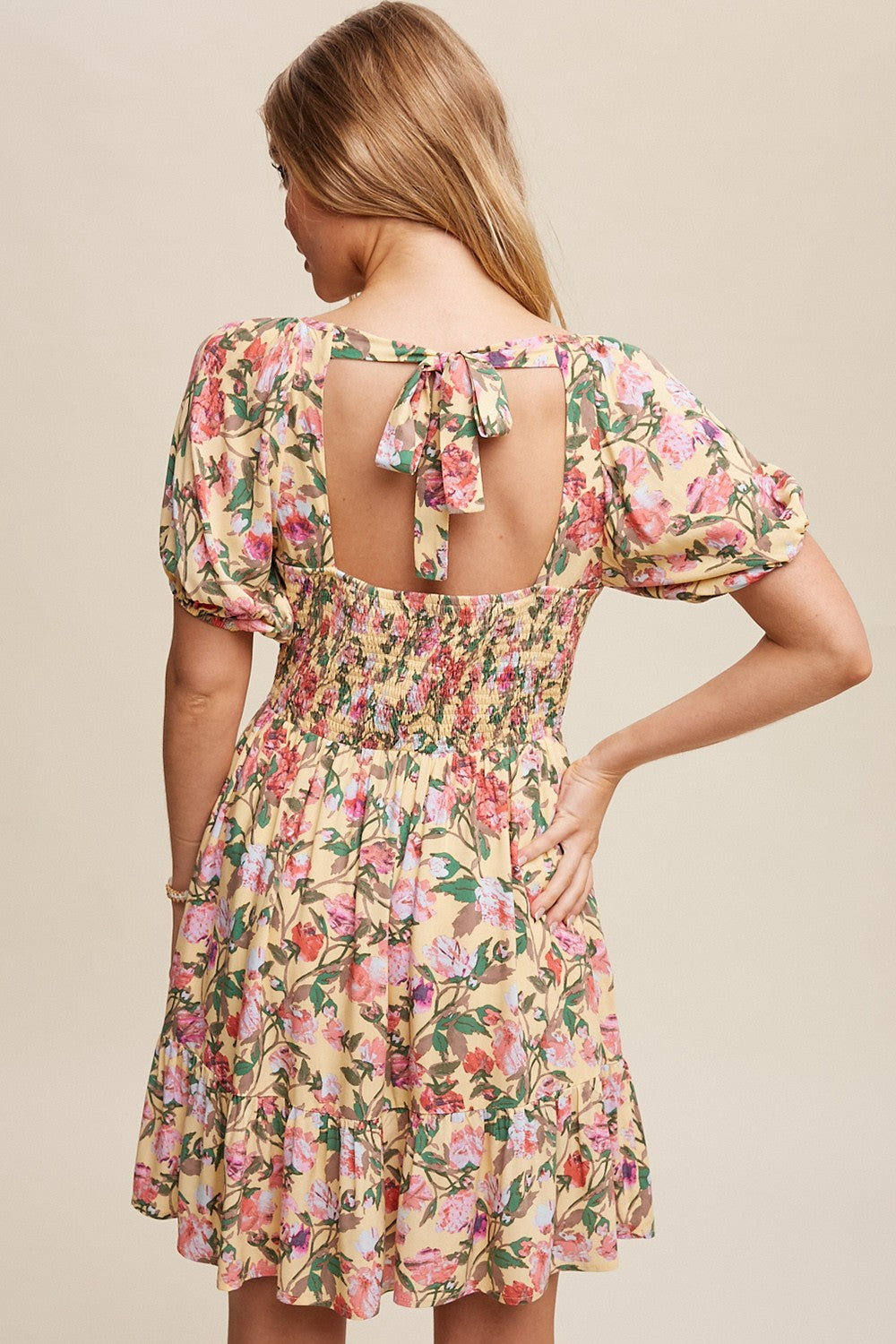 woman wearing a floral print smock dress with puff sleeves and a tie back detail