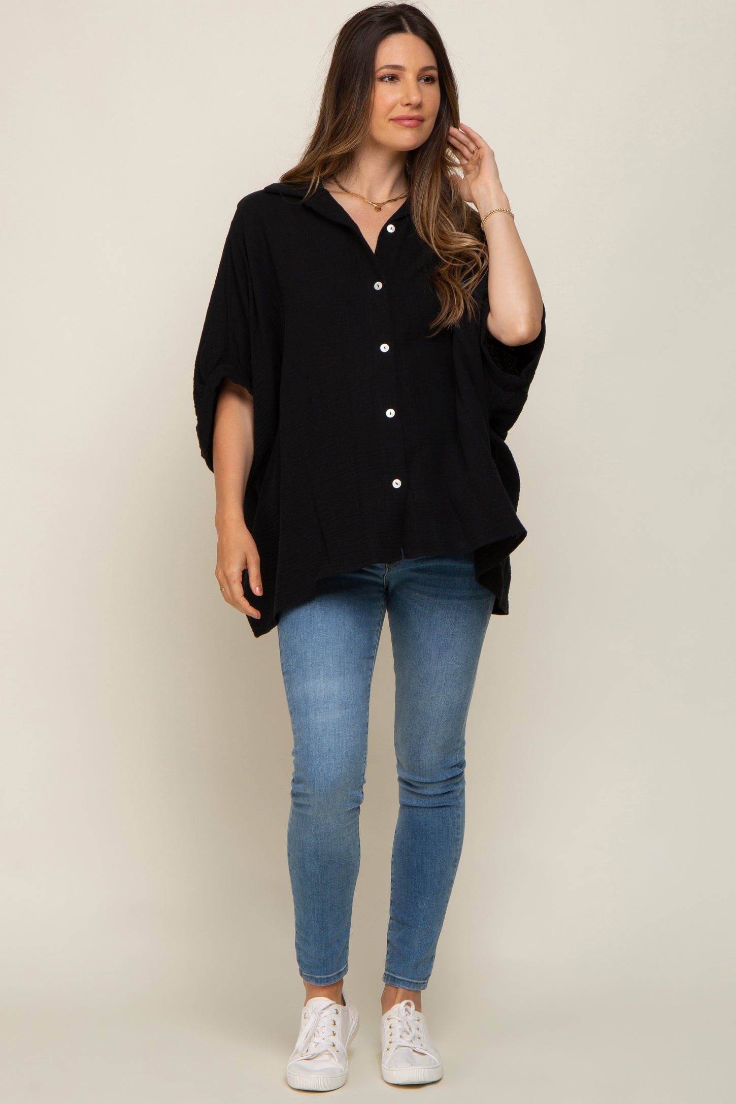 woman wearing black oversized button down shirt and blue skinny jeans with white sneakers