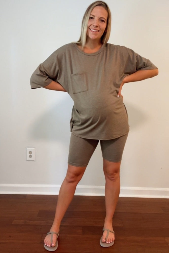 woman wearing a brown maternity t-shirt and matching bike shorts, showing her baby bump while standing with hands on hips