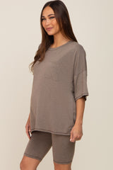 woman wearing a brown oversized maternity top with a pocket and matching bike shorts, displaying a baby bump