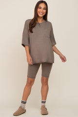 woman wearing a taupe maternity short sleeve lounge set with a pocket and matching bike shorts