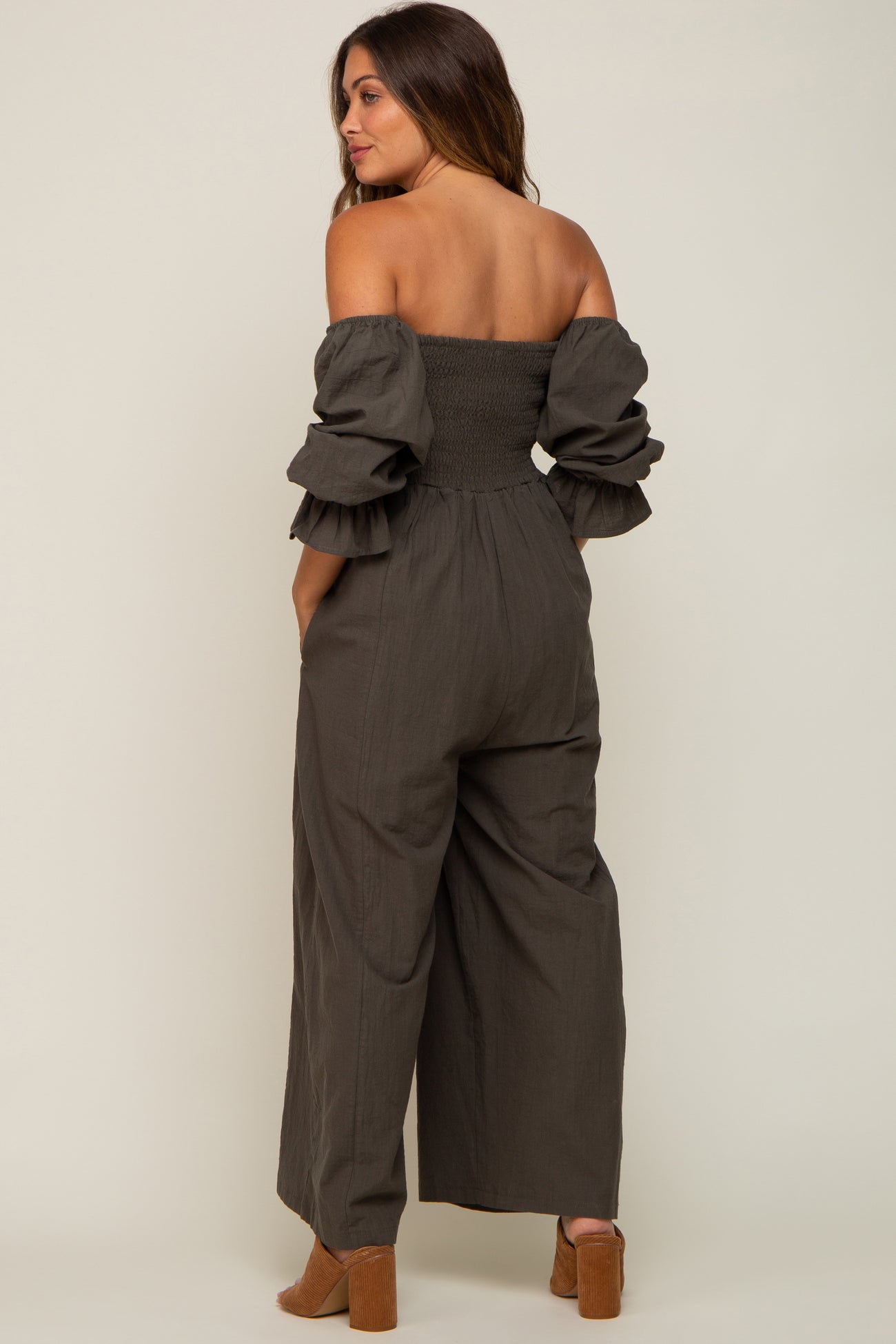 woman wearing a grey off-shoulder maternity jumpsuit with ruffled sleeves and wide legs