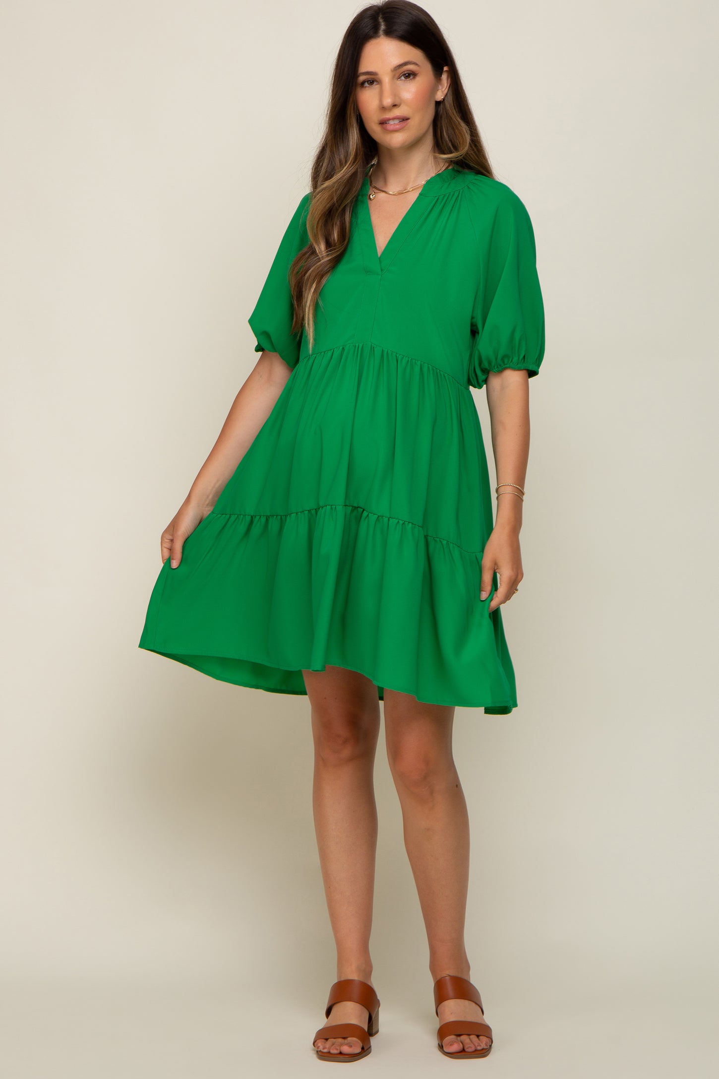 woman wearing a green tiered maternity dress with puff sleeves and brown sandals