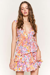 woman wearing a colorful floral print tiered mini dress with a deep v-neckline and ruffled details