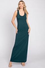 Woman wearing a sleeveless dark green maxi dress with a scoop neckline and clear sandals