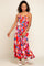 Woman wearing a colorful abstract print tiered maxi dress with spaghetti straps and white platform sandals