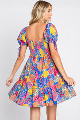 woman wearing a colorful tropical fruit print mini dress with puff sleeves and a smocked back