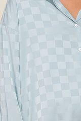 Close-up of a light blue satin button-down shirt with a tonal checkered pattern