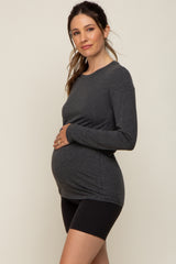 pregnant woman in charcoal grey long sleeve maternity top and black leggings holding her baby bump