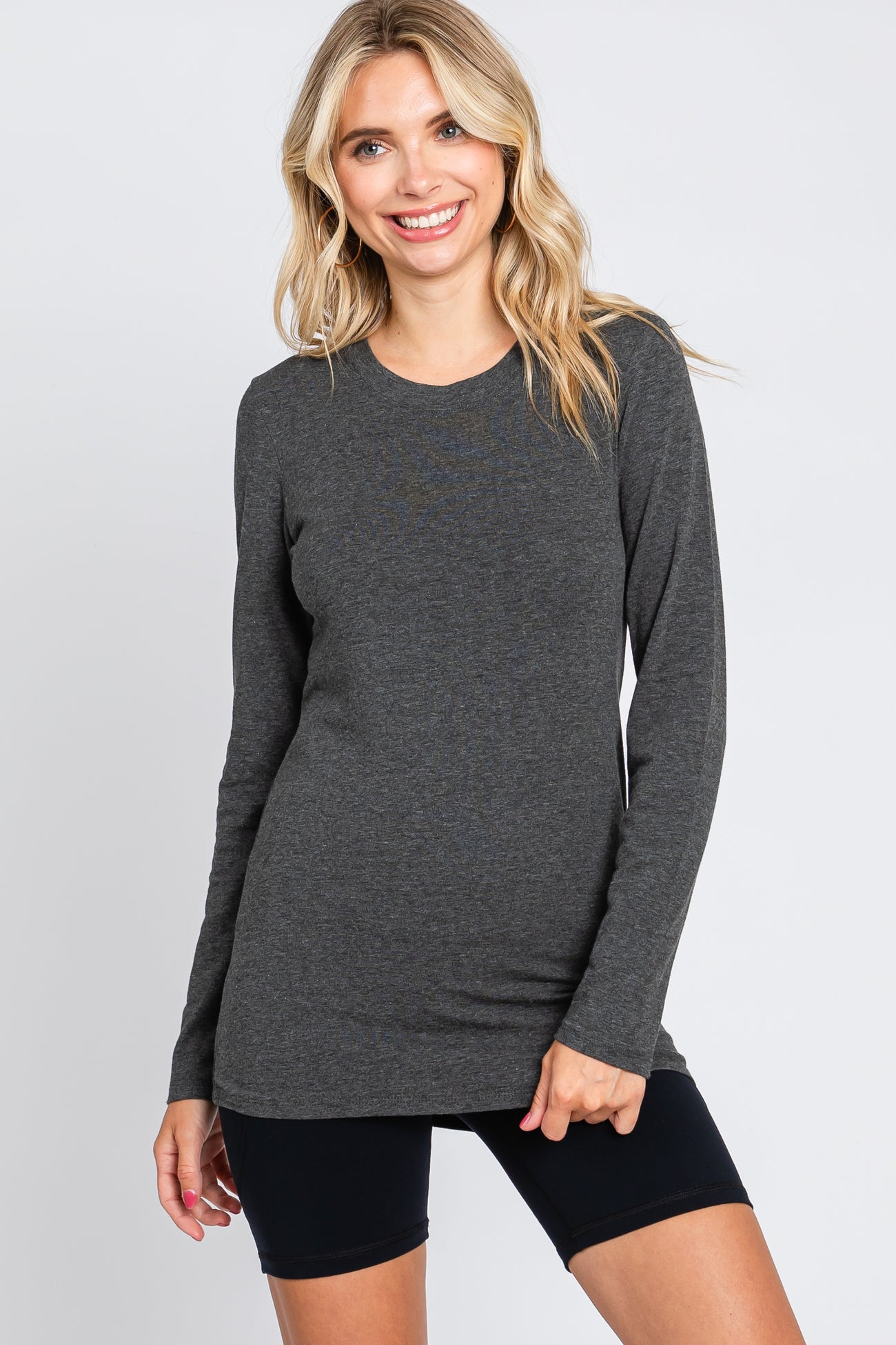 woman wearing a dark gray long sleeve top with a round neckline and slim fit, paired with black bike shorts