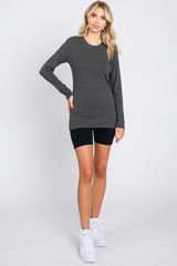 woman wearing a dark gray long sleeve shirt with black bike shorts and white sneakers