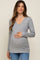 woman wearing a gray long sleeve maternity top with a v-neck and holding her baby bump
