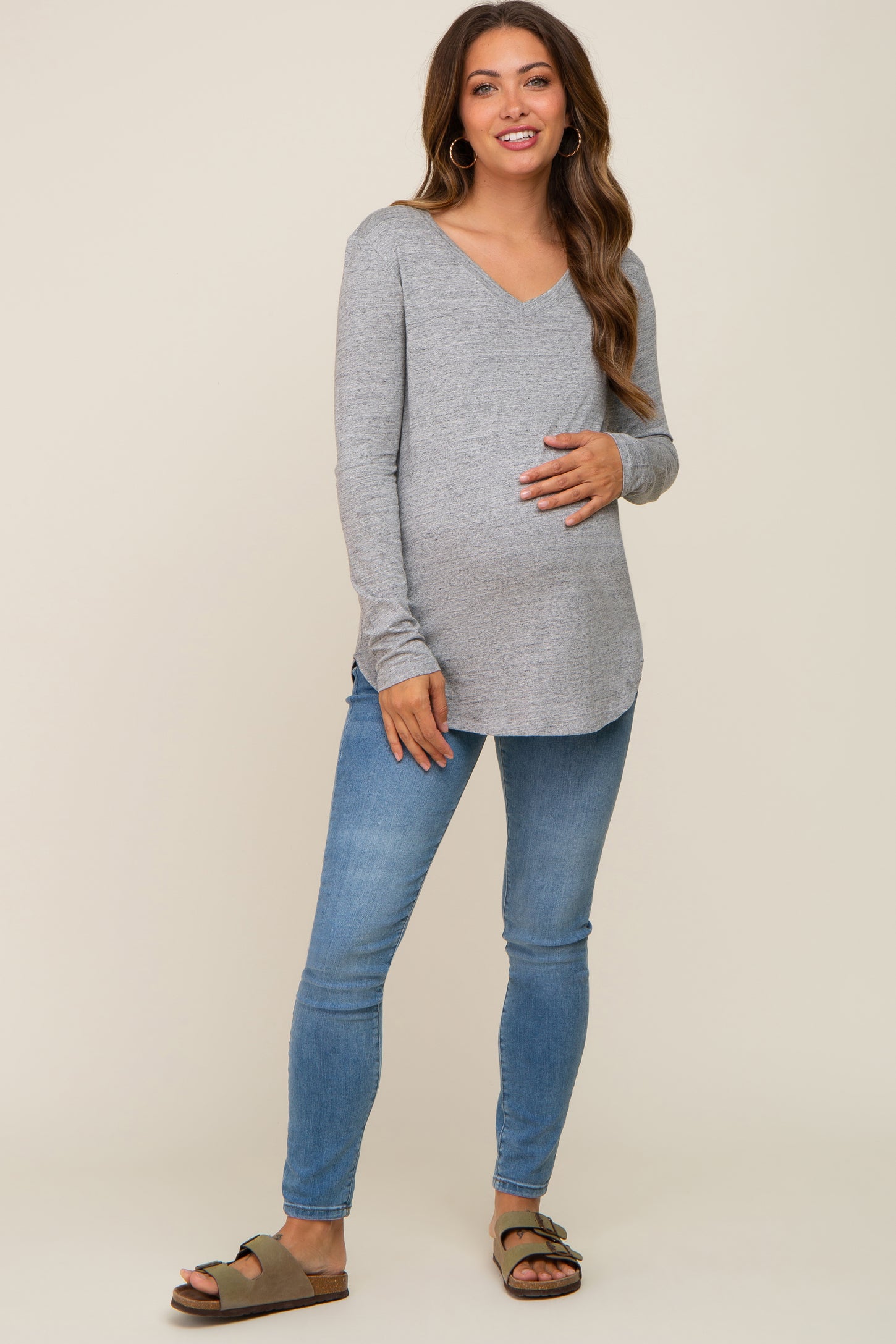 pregnant woman wearing grey long sleeve v-neck maternity top and blue skinny jeans