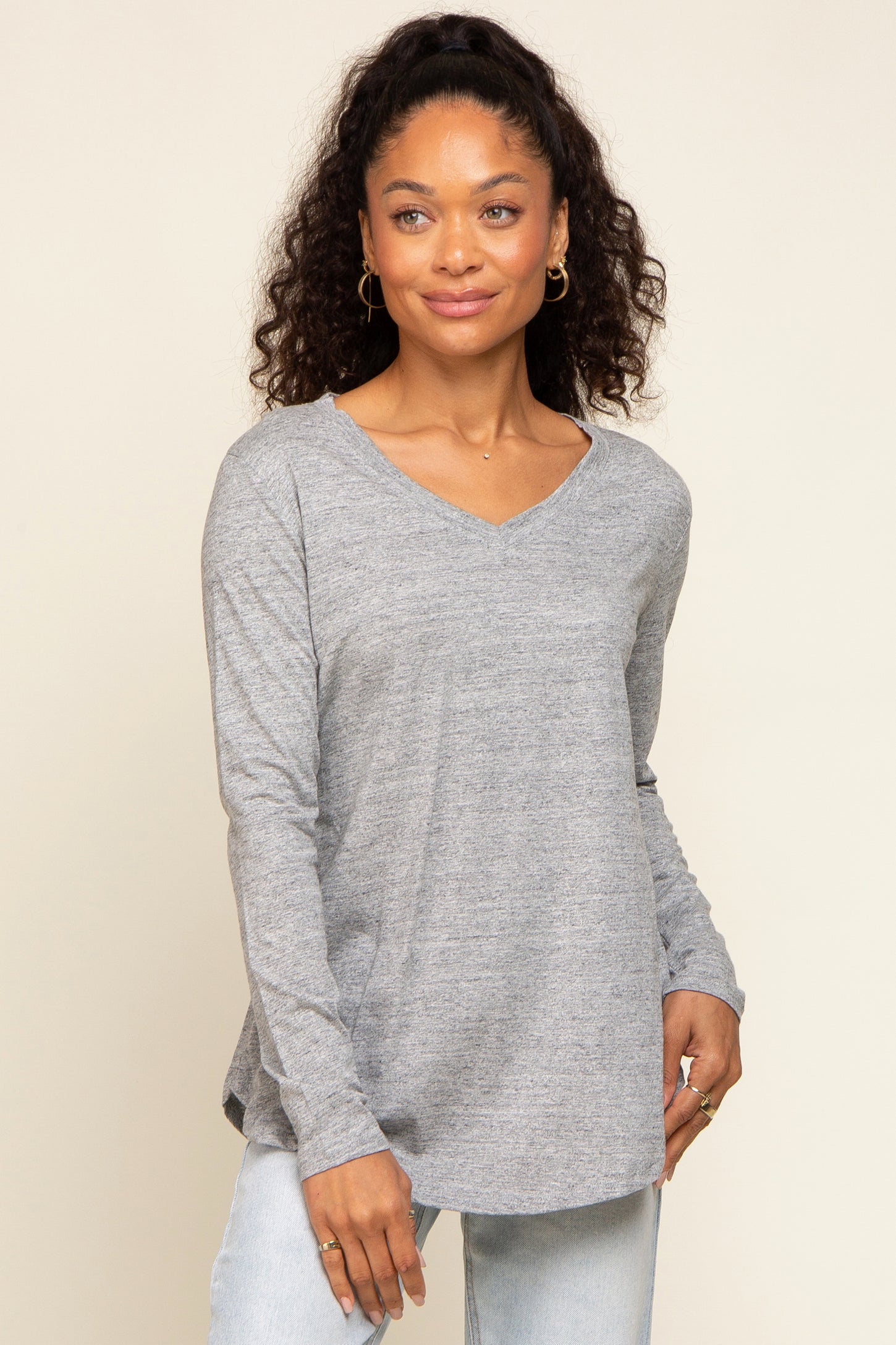 woman wearing a grey long sleeve v-neck t-shirt and light wash jeans