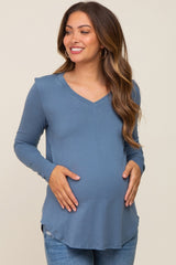 woman wearing a blue long sleeve maternity top and holding her baby bump