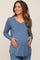 woman wearing a blue long sleeve maternity top and holding her baby bump