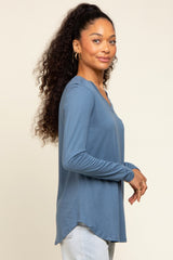 woman wearing a blue long sleeve top with a v-neck and a slightly curved hem
