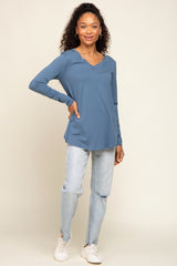 woman wearing a blue long sleeve top with a v-neck and distressed light wash jeans