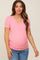 woman wearing a light pink maternity short sleeve v-neck top and showing her baby bump with blue distressed jeans