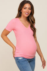 woman wearing a pink short sleeve maternity top with a v-neck and visible baby bump
