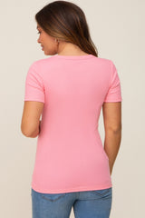 woman wearing a light pink short sleeve maternity top seen from the back