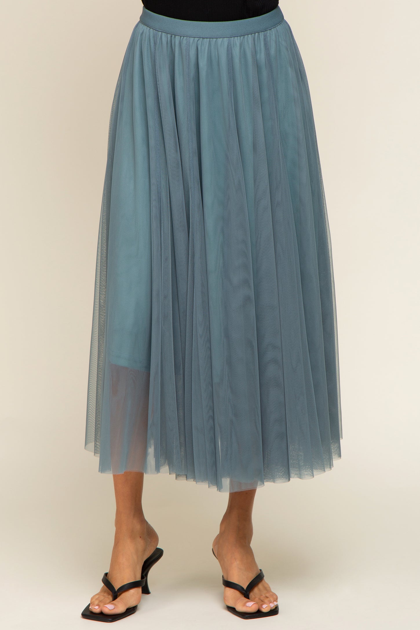woman wearing a sheer teal tulle midi skirt with an elastic waistband and flowy layered design