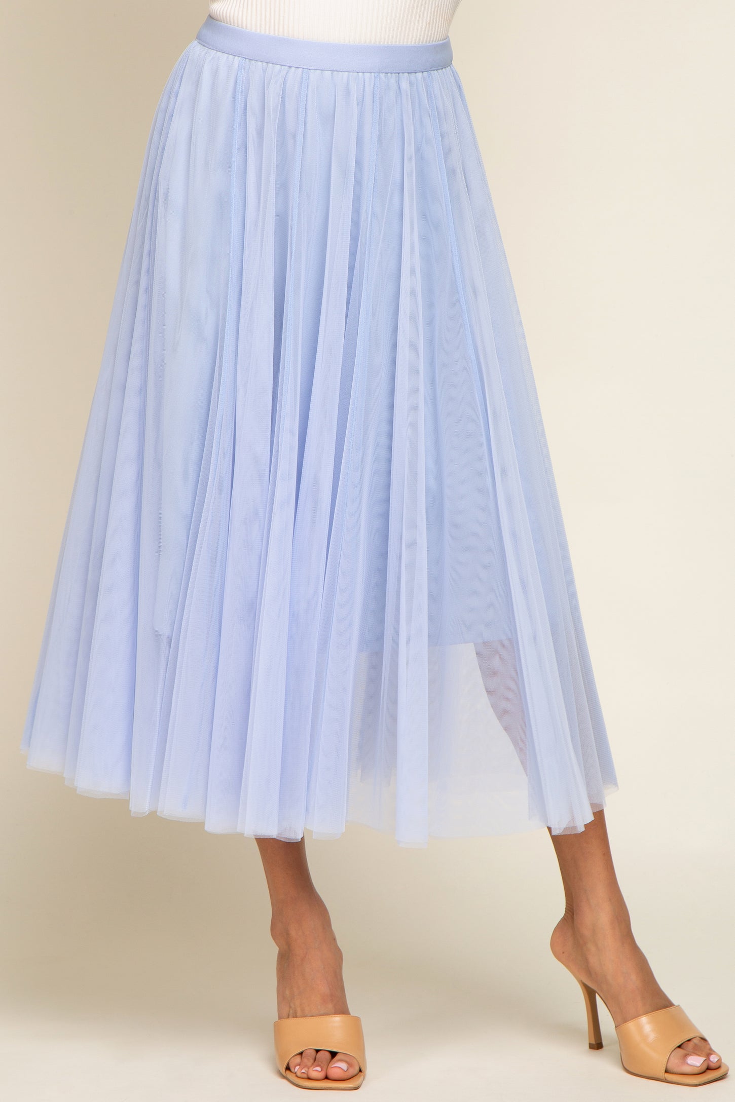 woman wearing a light blue pleated tulle midi skirt with a flowy design and open toe heels
