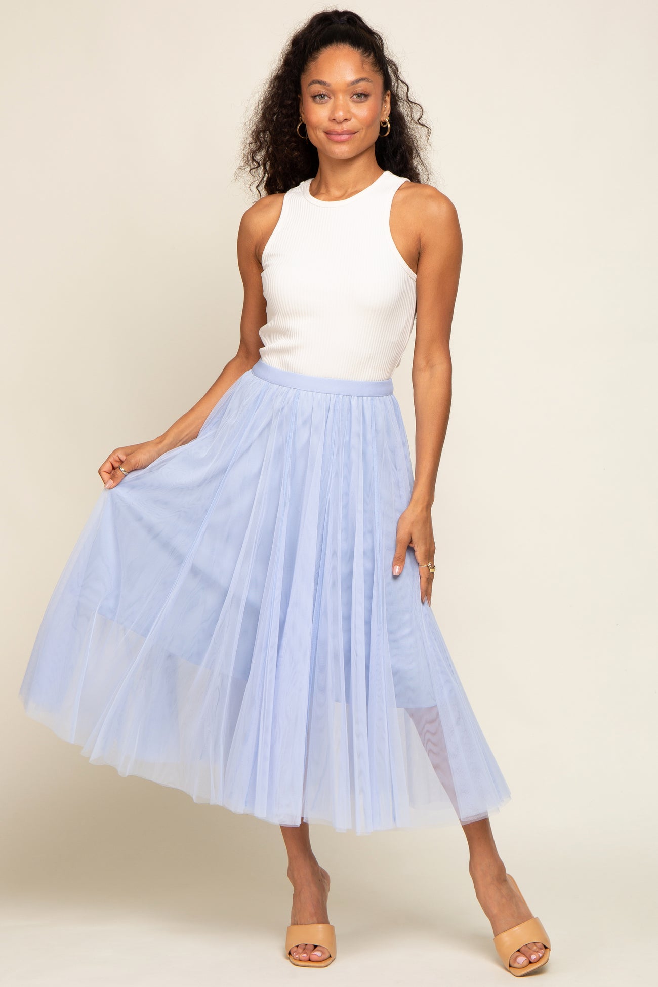 woman wearing a white ribbed tank top and a light blue tulle maxi skirt