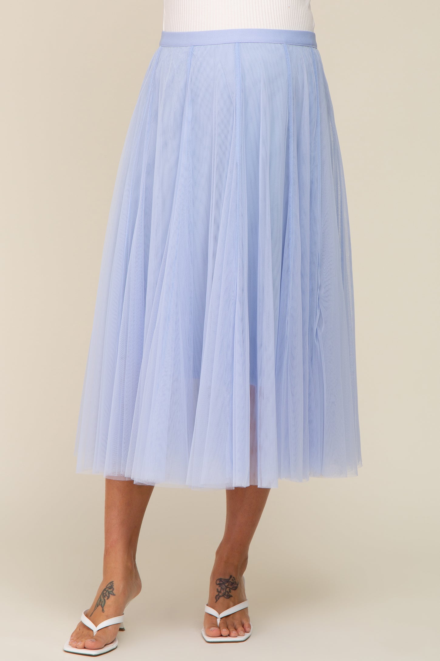 woman wearing a light blue maternity tulle midi skirt with a flowy silhouette and elastic waistband