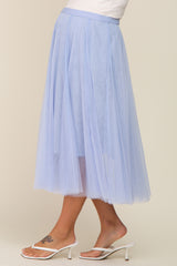 woman wearing a light blue tulle maternity skirt with a flowy design, standing in a side profile view