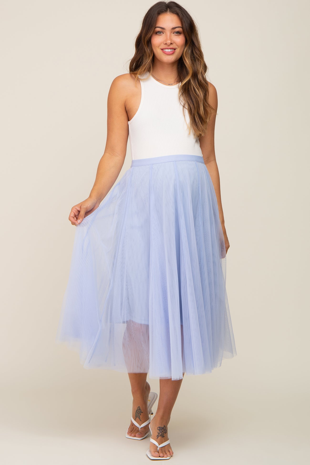 woman wearing a white sleeveless top and a light blue tulle maternity skirt