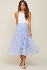 woman wearing a light blue maternity tulle skirt with a white sleeveless top and smiling
