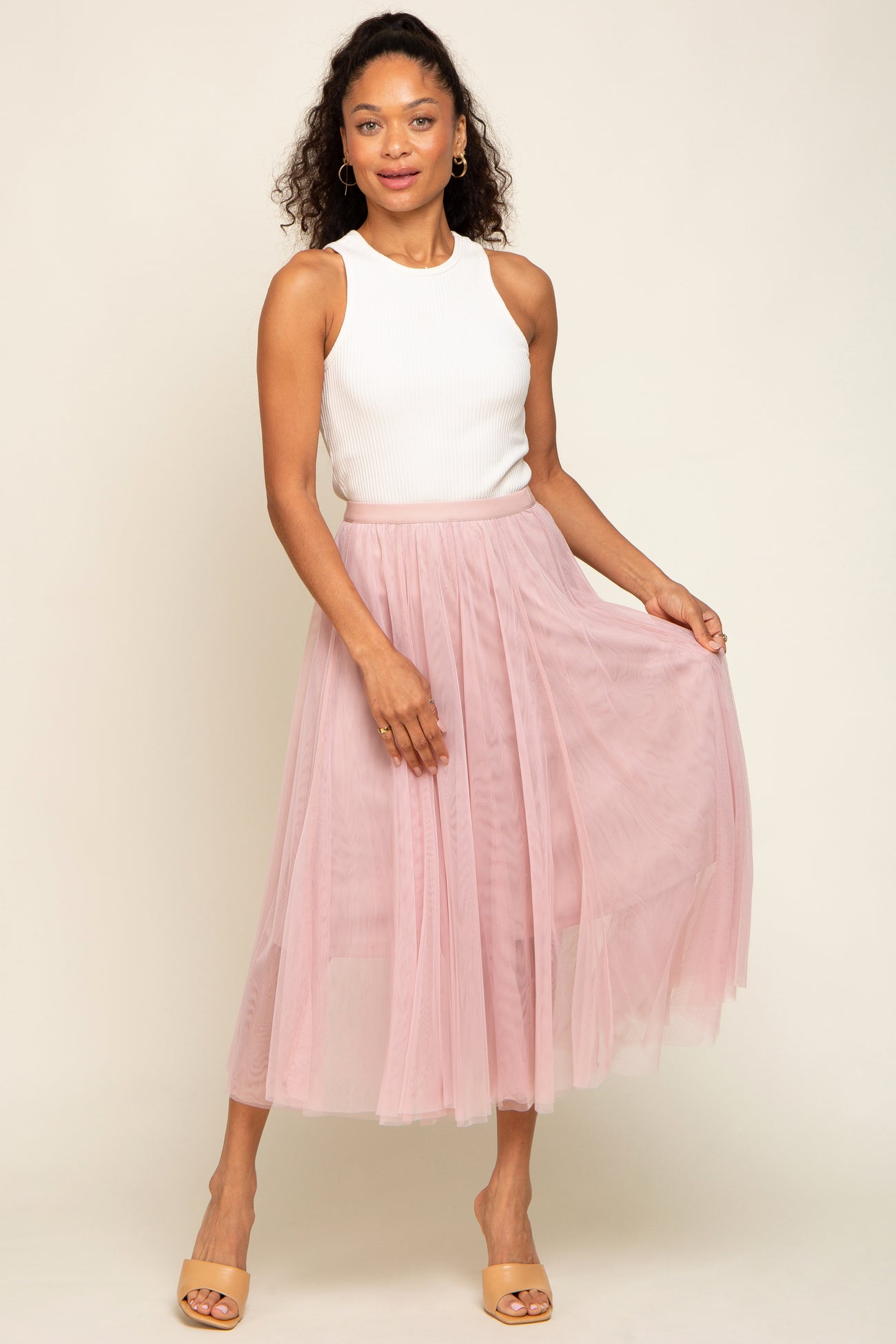 woman wearing a white ribbed sleeveless top and a light pink pleated tulle midi skirt